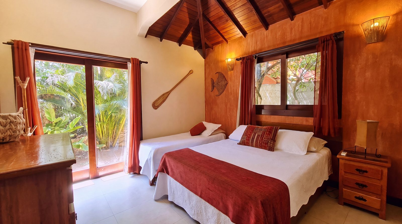 Jungle Hideaway: the two beds under the red curtains and the glass door to the palms