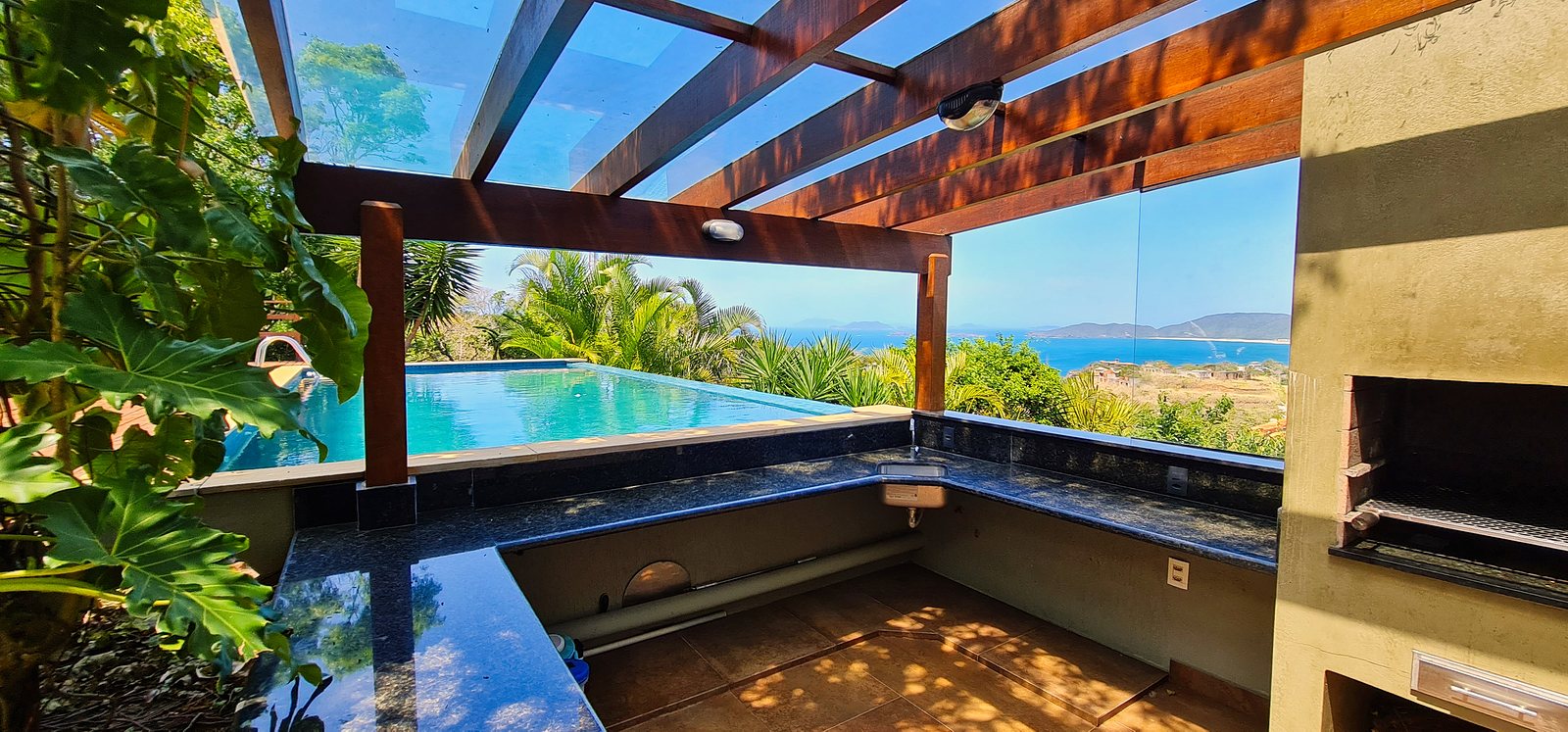 The poolside bar counter under the pergola, the pool and the sea behind