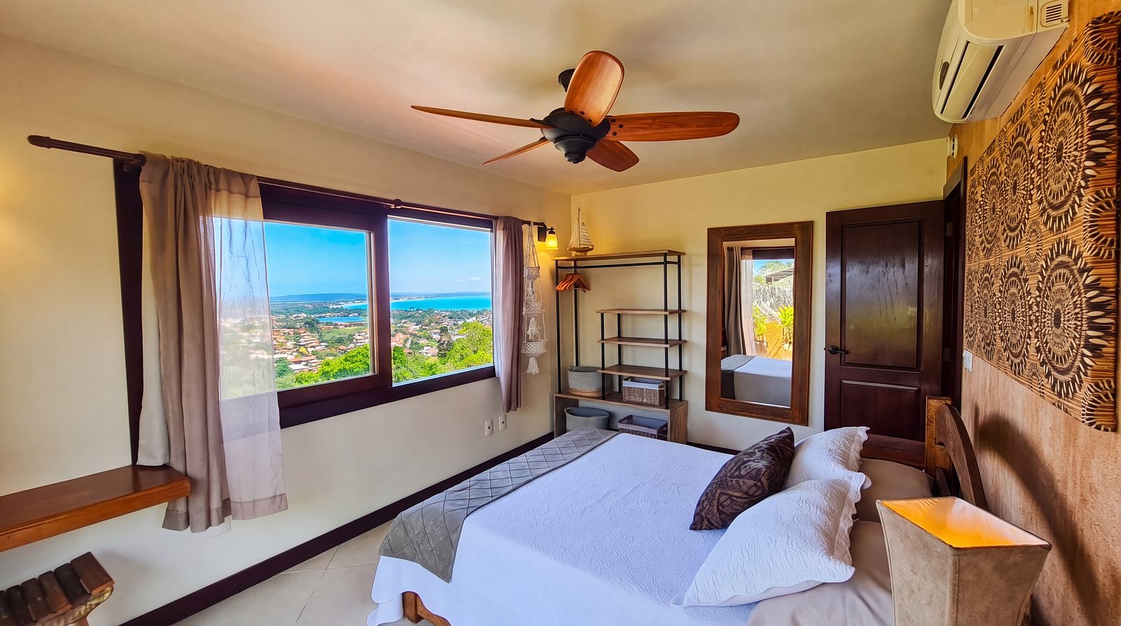 Sunset Suite: the bed, the mandala wall and the wide window over the town and the lagoon